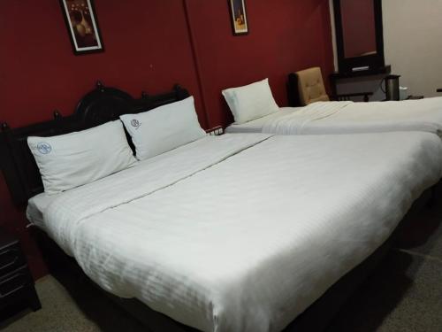 two beds in a hotel room with white sheets at Hotel Seven Roads in Kodaikānāl