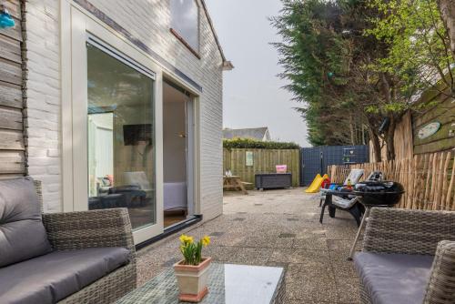 een patio met een bank en stoelen in een tuin bij BeachHouse Oase aan Zee in Noordwijk