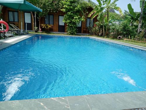 a swimming pool with blue water in front of a house at Tam Coc Village Bungalow in Ninh Binh