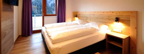 Schlafzimmer mit einem großen Bett mit einem Kopfteil aus Holz in der Unterkunft Apart Alpenglüh´n in Spiss