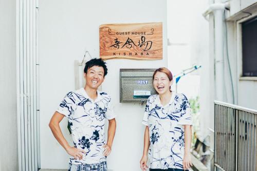 a man and a woman standing in front of a building at ゲストハウス喜舎場 in Ishigaki Island