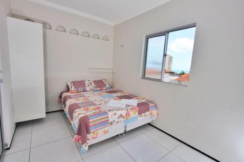 a white bedroom with a bed and a window at Residencial Santa Lucia in Fortaleza