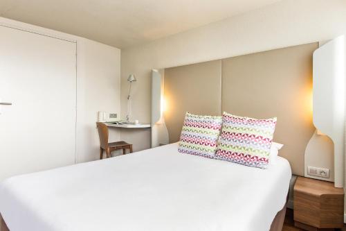 ein Schlafzimmer mit einem großen weißen Bett mit zwei Kissen in der Unterkunft Campanile Amiens - Glisy in Glisy