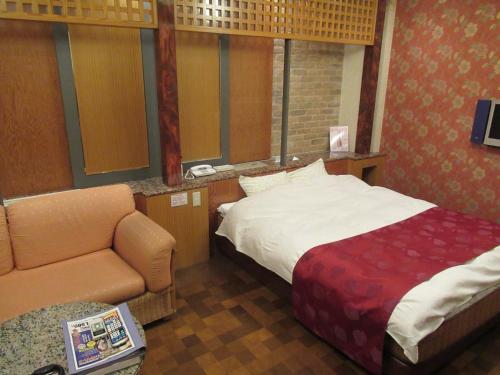 a hotel room with a bed and a chair at Hotel Shuyukan (Adult Only) in Izumi-Sano