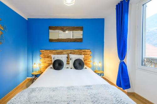 - une chambre bleue avec un lit et un mur bleu dans l'établissement Élégance contemporaine près des Thermes., à Allevard