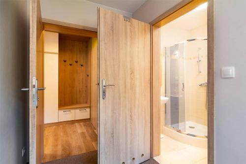 a bathroom with a wooden door leading to a shower at Róża Sudetów Apartamenty in Duszniki Zdrój