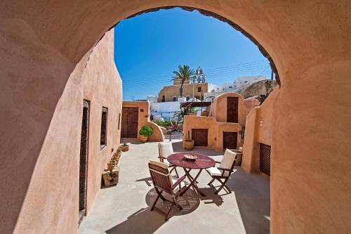 an archway with a table and chairs on a patio at Azalea Houses in Oia