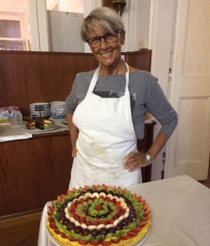 een vrouw in een schort die voor een taart staat bij Hotel Villa Bonera in Genua