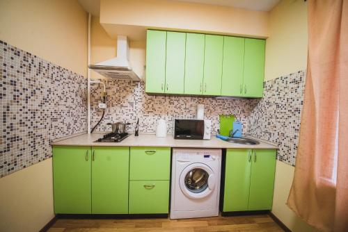 a kitchen with green cabinets and a washing machine at Kvartira Klassika na Prospekte Kultury 11 in Omsk