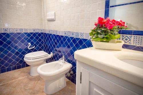a bathroom with a toilet and a sink with a vase of roses at Villa Isuledda Prestige in San Teodoro