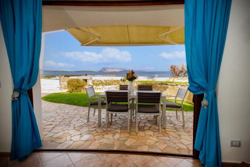 a table with chairs and a view of the ocean at Villa Isuledda Prestige in San Teodoro