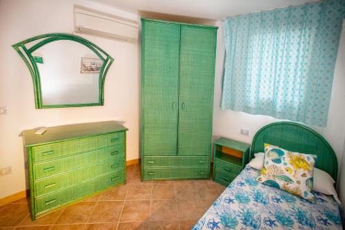 a bedroom with green cabinets and a bed and a mirror at Villa Isuledda Prestige in San Teodoro