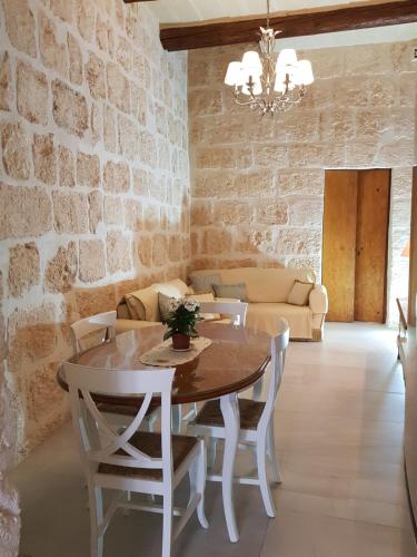 a dining room with a table and chairs and a brick wall at Tal-Kampjin in Mellieħa