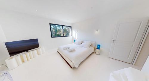 a white bedroom with a bed and a flat screen tv at HOUSE ZYX in Le Touquet-Paris-Plage