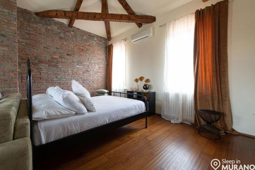 ムラーノにあるDUOMO Murano Apartment with Canal viewのレンガの壁、ベッド付きのベッドルーム1室