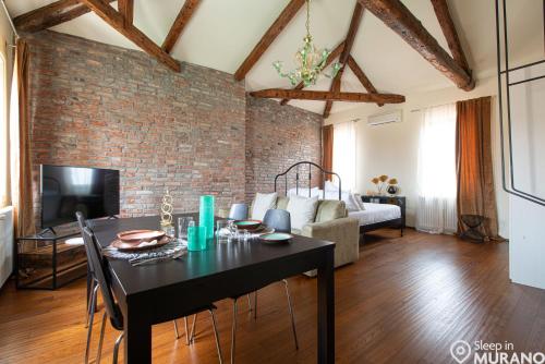 een woonkamer met een tafel en een bakstenen muur bij DUOMO Murano Apartment with Canal view in Murano