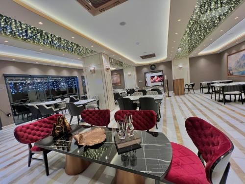 MQ Hotel Suites في Arnavutköy: مطعم بطاولة زجاجية وكراسي حمراء