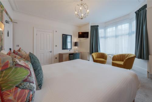 a bedroom with a large white bed and chairs at Florence Gardens Boutique Hotel and Restaurant in Portsmouth