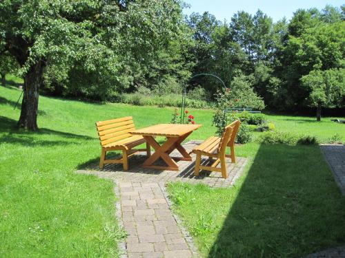 a wooden picnic table and two chairs in a park at Haus Hilda Fechtig in Ühlingen-Birkendorf