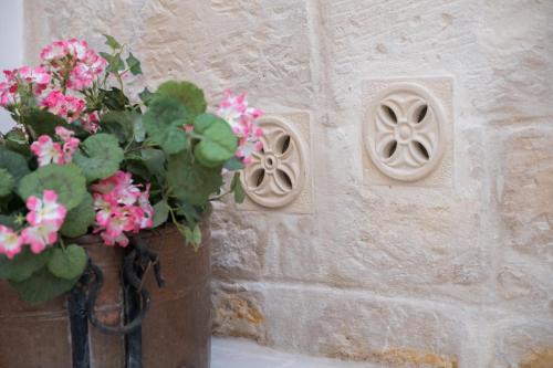 a vase filled with pink flowers next to a stone wall at Amatè Suite in Lecce