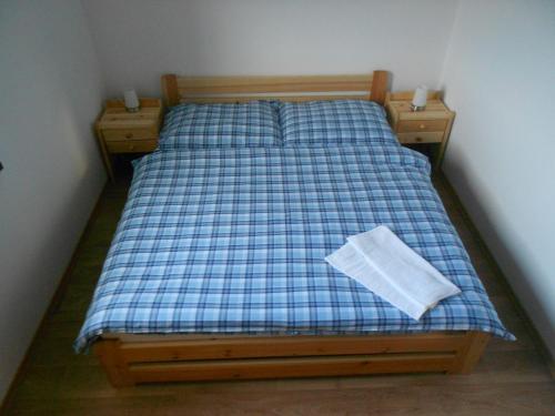 a bed with a blue and white plaid sheets and a pillow at Apartmán u Hovorků in Borová Lada