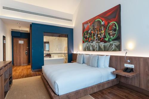 a bedroom with a white bed and a painting on the wall at QUU HOTEL Chiang Mai in Chiang Mai