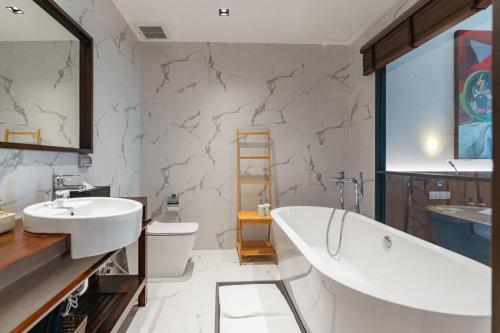 a bathroom with a tub and a sink at QUU HOTEL Chiang Mai in Chiang Mai