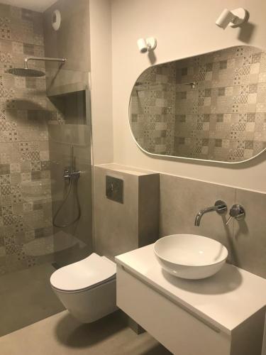 a bathroom with a sink and a toilet and a mirror at Apartament AG5 in Gdańsk