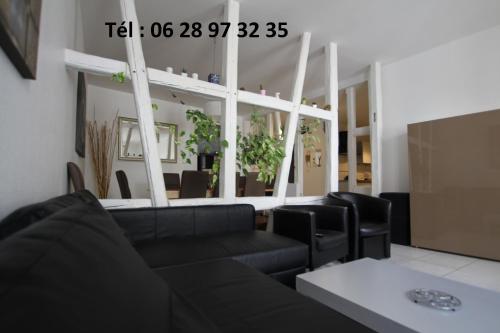 Una sala de estar con un sofá negro y una mesa. en Gite hyper centre 10 pers, en Colmar