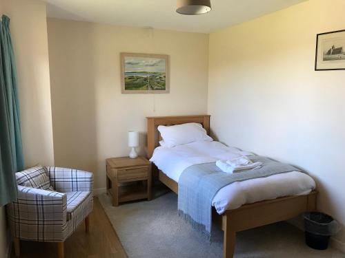 a small bedroom with a bed and a chair at The Old Schoolhouse in Saint Margarets Hope