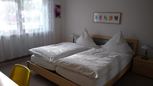 a bedroom with a bed with white sheets and pillows at Haus Waldblick - Ferienwohnung Sonnenplätzchen, Bad Bergzabern in Bad Bergzabern