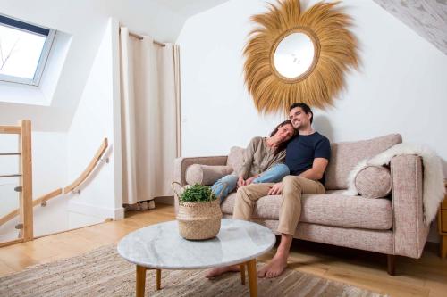 un homme et une femme assis sur un canapé dans un salon dans l'établissement Gîtes de La Vesée, à La Chapelle dʼArmentières