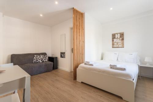 a white bedroom with a bed and a couch at FLH Marquês Charming Flats in Lisbon