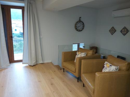 a living room with two chairs and a clock on the wall at Casa da Padaria in Folgosa