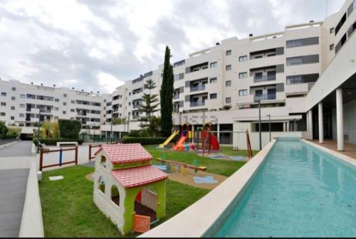 uma piscina com parque infantil e edifícios de apartamentos em Magnífico apartamento en El Pto de Sta María, aire acc, piscina, zona niños y padel em El Puerto de Santa Maria