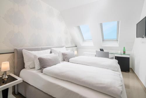 a white bedroom with a bed with white sheets and pillows at Best Western Plus Celebrity Suites in Vienna