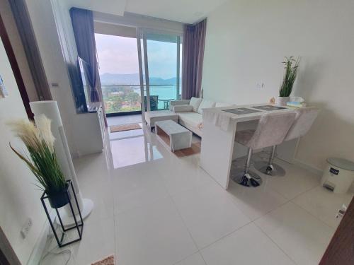 a white living room with a table and a couch at Delmare Beachfront Bangsaray Premium Condominium in Bang Sare