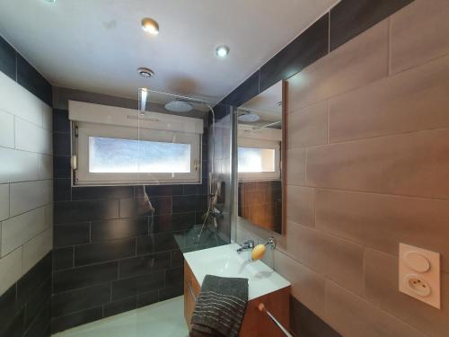 une salle de bain avec un lavabo et un miroir dans l'établissement Chez Georgette***, à Gérardmer