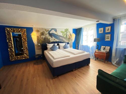 Schlafzimmer mit einem Bett mit blauen Wänden und einem Spiegel in der Unterkunft Boutique Hotel & Bio Wirtshaus Schwarzer Bock in Ansbach