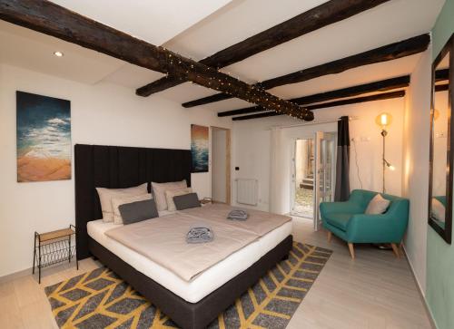 een slaapkamer met een groot bed en een blauwe stoel bij Suite - Sweet MayLeen in Merano