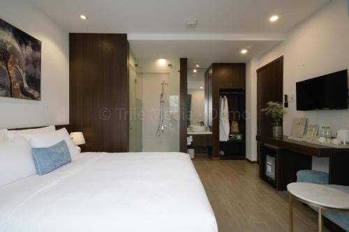 a bedroom with a large white bed and a bathroom at Lion King Hotel in Hoi An