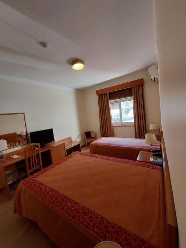 a hotel room with two beds and a desk at Hotel Aguiar da Pena in Vila Pouca de Aguiar