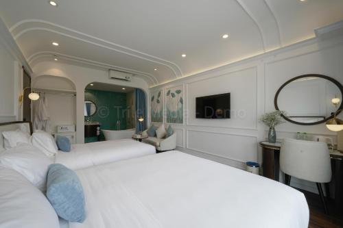 a bedroom with two white beds and a bathroom at Lion King Hotel in Hoi An