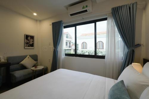 a bedroom with a bed and a window and a couch at Lion King Hotel in Hoi An