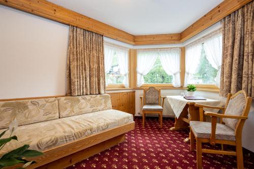 uma sala de estar com um sofá, uma mesa e janelas em Hotel Garni Tyola em Ischgl