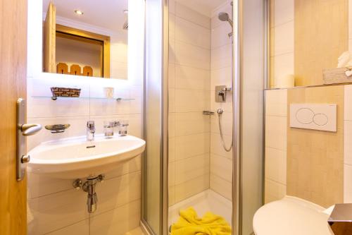 uma casa de banho com um chuveiro, um lavatório e um WC. em Hotel Garni Tyola em Ischgl