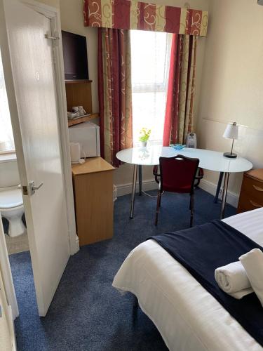 a hotel room with a bed and a table and a window at Victoria House - Self Catering Quiet Guesthouse - Adult Singles and Couples Only in Blackpool