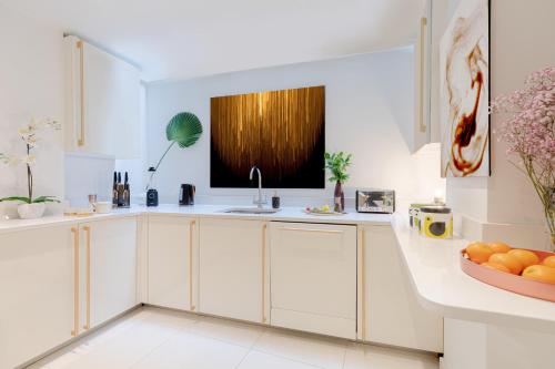 a kitchen with white cabinets and a sink at Explore the MOST EXQUISITE West-End from a Harrods FAMILY and COUPLE HOME in London