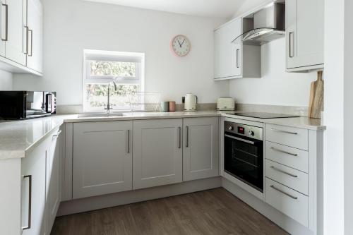 a white kitchen with white cabinets and a window at Stylish Flat - Bowness centre with parking in Bowness-on-Windermere