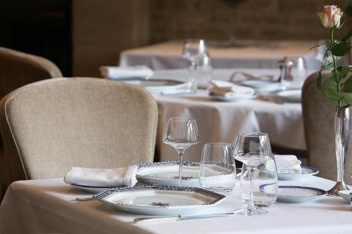 a table with white plates and wine glasses on it at Hotel Restaurant Le Dauphin et Le Spa du Prieuré in Caen